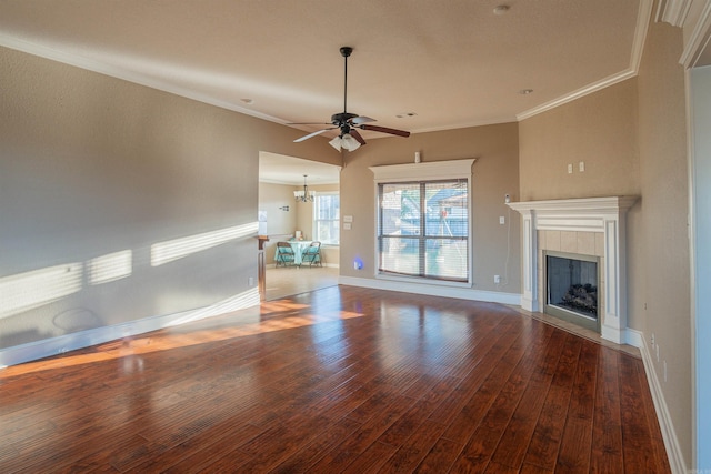 unfurnished living room featuring baseboards, hardwood / wood-style floors, crown molding, a fireplace, and ceiling fan with notable chandelier