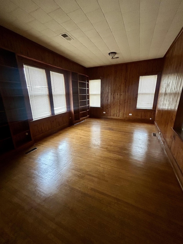 spare room featuring visible vents, wood walls, and wood finished floors