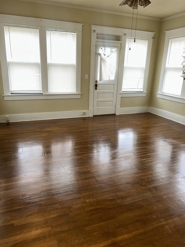 interior space with dark wood-type flooring, crown molding, and baseboards