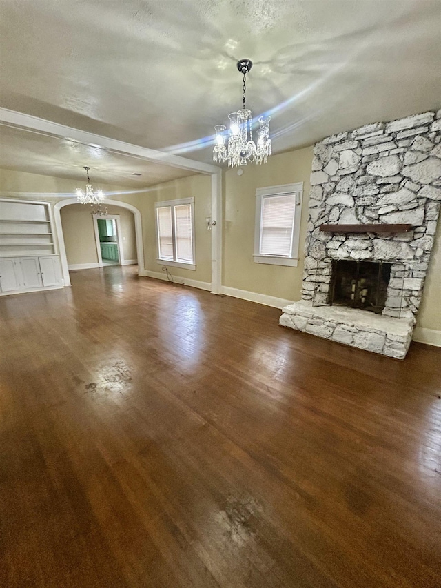 unfurnished living room featuring a healthy amount of sunlight, a fireplace, arched walkways, and a notable chandelier