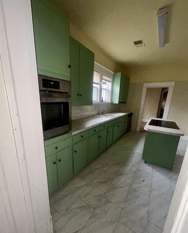 kitchen featuring green cabinetry, marble finish floor, light countertops, stainless steel oven, and a sink