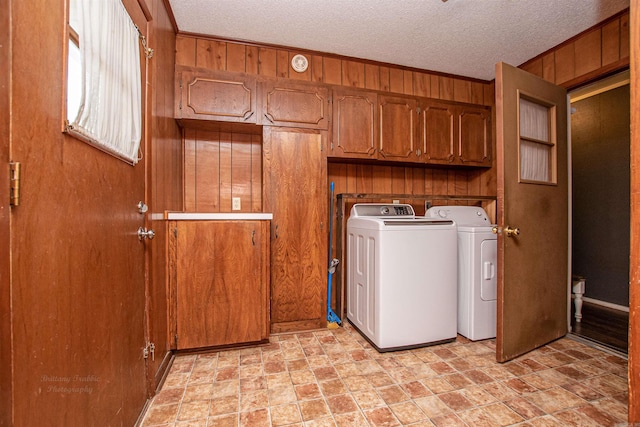 681 Sharp Ave, Camden, AR 71701 - washroom featuring wood walls, washing machine and dryer, cabinet space, a textured ceiling, and stone finish floors