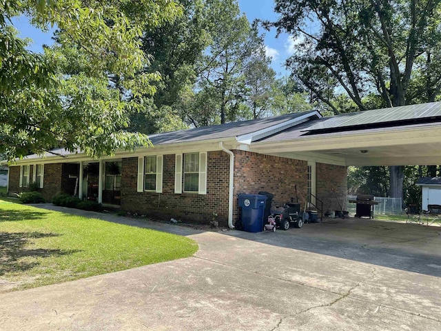 681 Sharp Ave, Camden, AR 71701 - view of front of house with driveway, a front lawn, brick siding, a carport, and solar panels