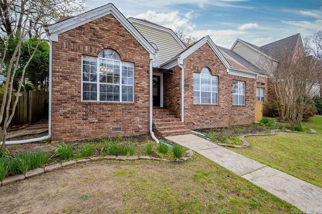 view of front of house with brick siding, crawl space, a front lawn, and fence