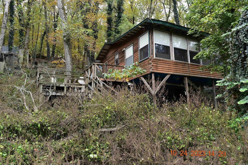 view of property exterior featuring a view of trees and a wooden deck