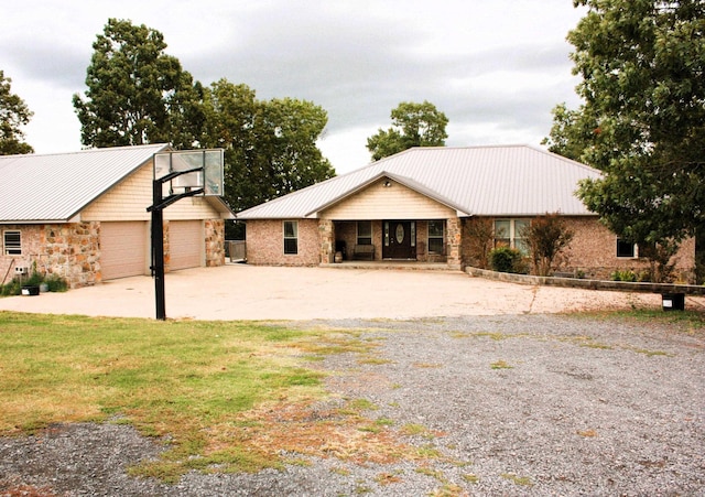 view of front of property with an outbuilding, stone siding, metal roof, and a detached garage