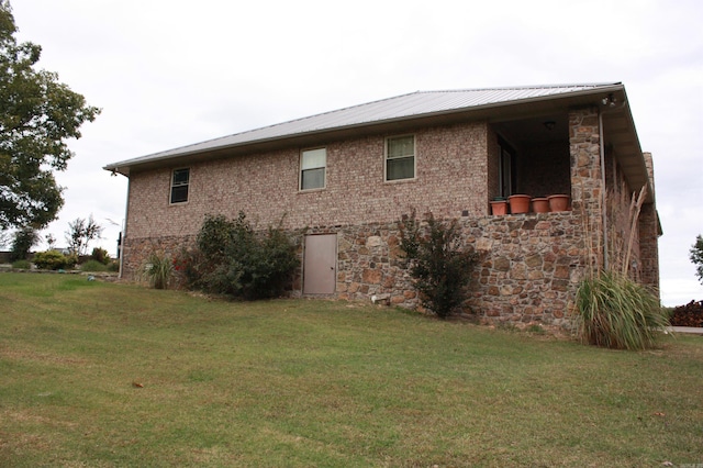 view of side of home with metal roof, a yard, brick siding, and stone siding