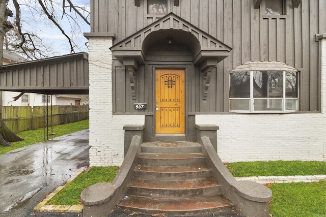 property entrance with fence, board and batten siding, and brick siding