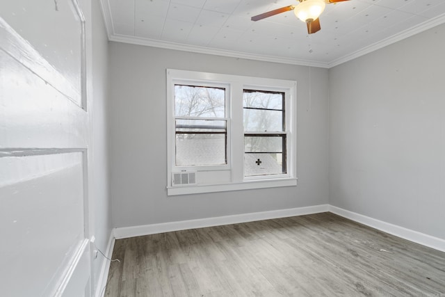 empty room featuring crown molding, wood finished floors, a ceiling fan, and baseboards