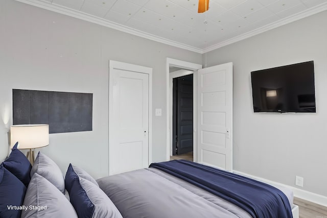 bedroom with a ceiling fan, baseboards, ornamental molding, and wood finished floors