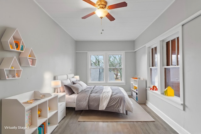 bedroom featuring a ceiling fan, baseboards, and wood finished floors