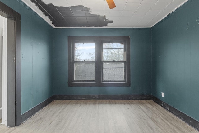 spare room with crown molding, wood finished floors, and baseboards