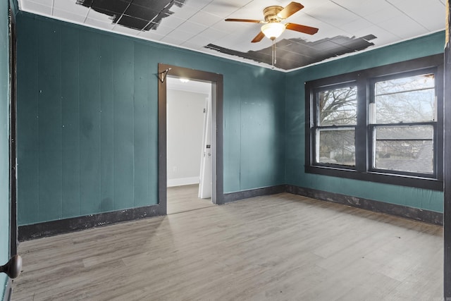 empty room with ceiling fan, wood finished floors, and baseboards