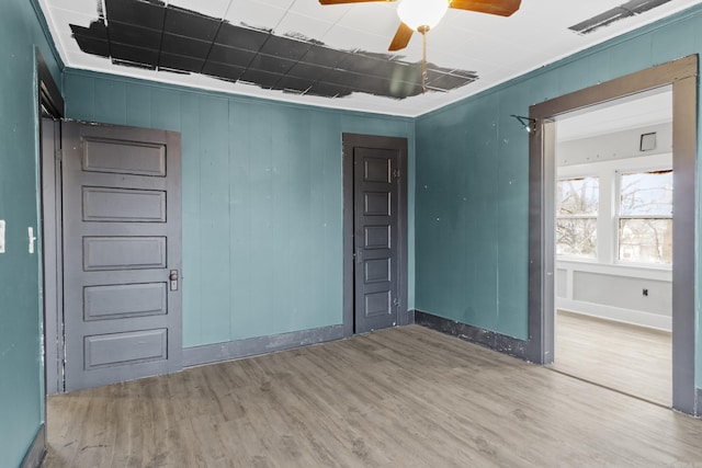 empty room with ceiling fan, wood finished floors, and baseboards