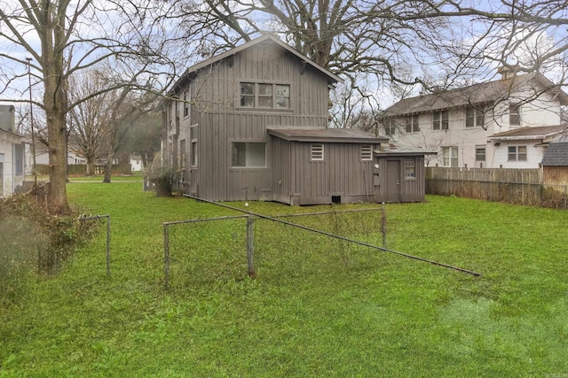 back of house with fence and a lawn