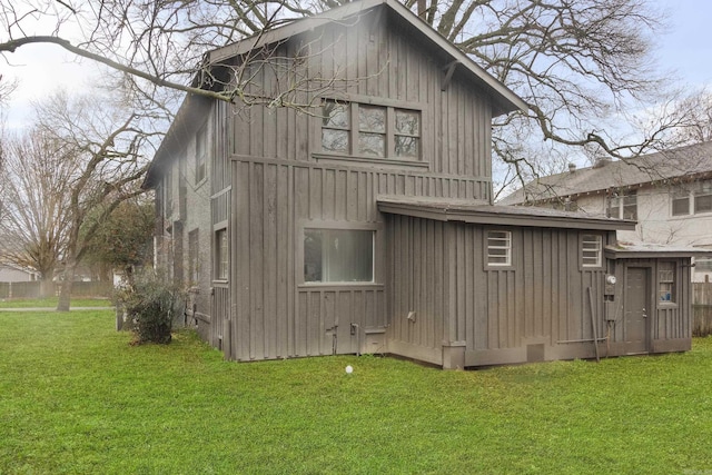 rear view of property featuring board and batten siding and a lawn