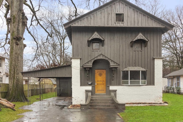 view of front of house with entry steps, driveway, brick siding, fence, and a front yard