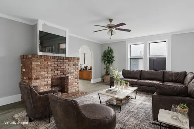 living room with ornamental molding, a fireplace, a ceiling fan, and baseboards