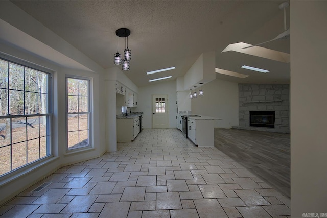 kitchen with white cabinets, open floor plan, vaulted ceiling, light countertops, and a sink