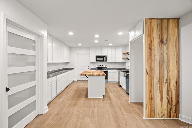 kitchen featuring black microwave, a kitchen island, white cabinetry, light wood-type flooring, and stainless steel electric range