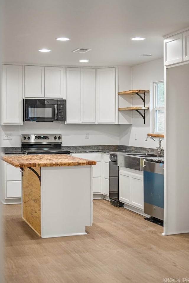 kitchen featuring stainless steel range with electric cooktop, white cabinets, butcher block countertops, black microwave, and dishwashing machine