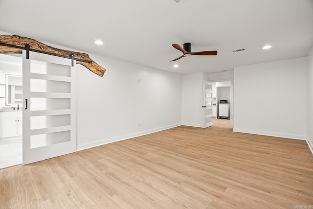 unfurnished living room with recessed lighting, a barn door, ceiling fan, and light wood-style flooring