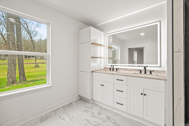 full bathroom with double vanity, marble finish floor, baseboards, and a sink