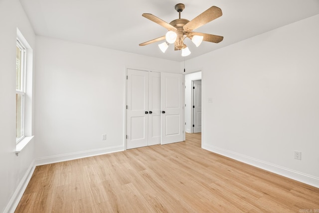 spare room with ceiling fan, light wood finished floors, and baseboards