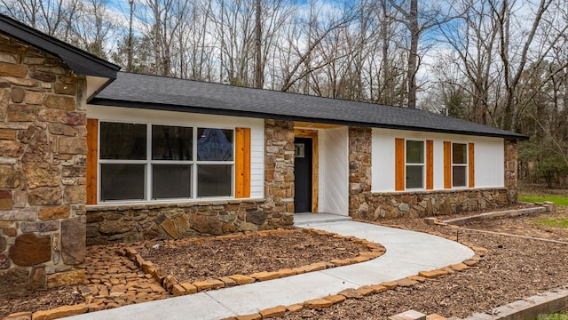 view of front facade with stone siding and roof with shingles