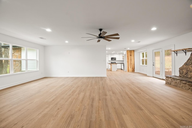 unfurnished living room featuring ceiling fan, light wood finished floors, plenty of natural light, and visible vents