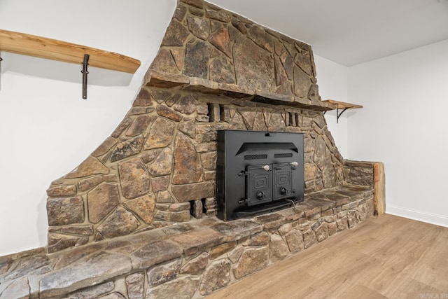 interior details with a wood stove, baseboards, and wood finished floors