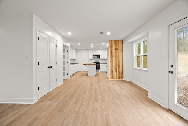 unfurnished living room featuring light wood finished floors, a wealth of natural light, and recessed lighting