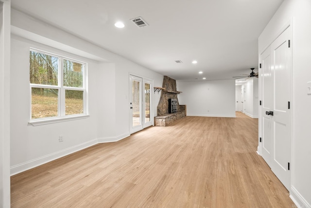 unfurnished living room with a stone fireplace, recessed lighting, visible vents, baseboards, and light wood-style floors