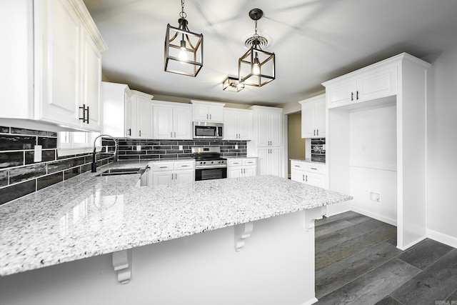 kitchen with dark wood-style flooring, a peninsula, a sink, stainless steel appliances, and backsplash