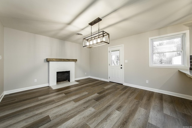 unfurnished living room featuring dark wood-style flooring, a brick fireplace, visible vents, and baseboards