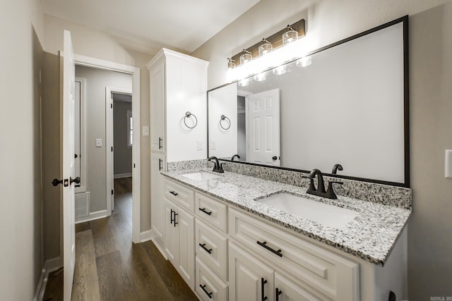 bathroom with double vanity, a sink, baseboards, and wood finished floors