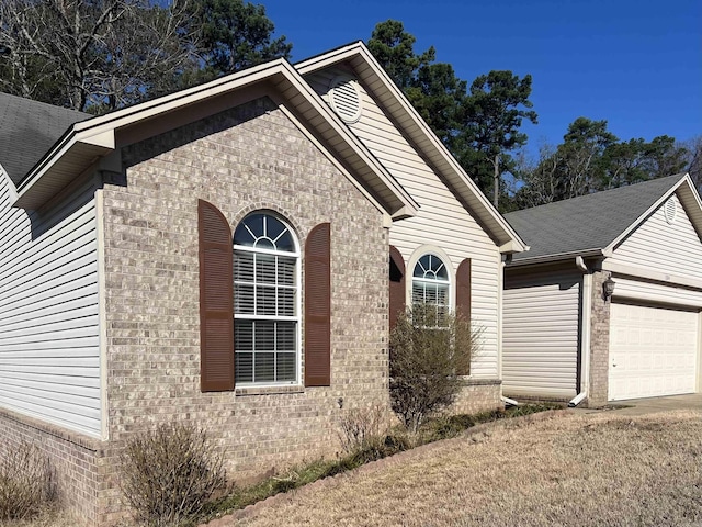 view of front facade with brick siding, roof with shingles, and an attached garage