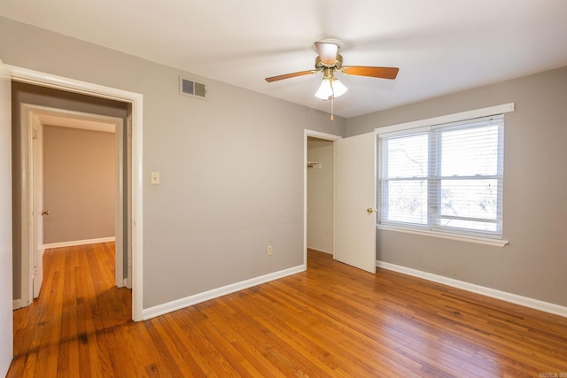 unfurnished bedroom with a ceiling fan, light wood-type flooring, visible vents, and baseboards