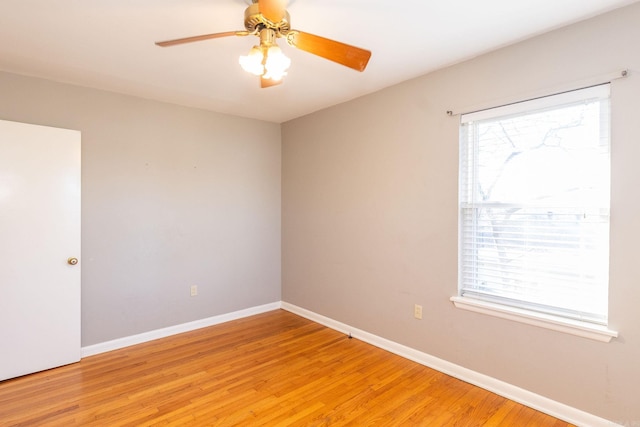 spare room with light wood finished floors, a ceiling fan, and baseboards