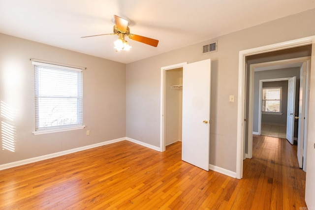 unfurnished bedroom featuring light wood-style flooring, a ceiling fan, visible vents, baseboards, and a closet