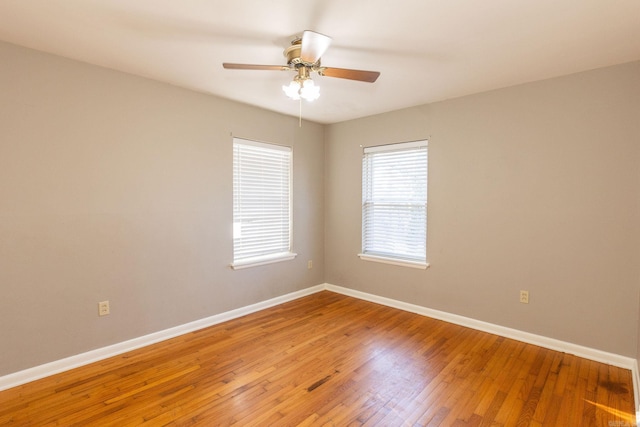 unfurnished room with wood-type flooring, a ceiling fan, and baseboards