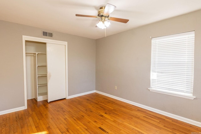 unfurnished bedroom with ceiling fan, visible vents, baseboards, light wood-style floors, and a closet