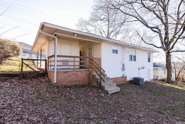 rear view of house with covered porch, central AC, and fence