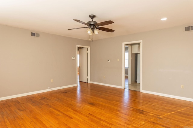 spare room featuring a ceiling fan, light wood-style flooring, visible vents, and baseboards