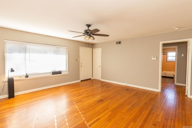 unfurnished room featuring light wood finished floors, baseboards, visible vents, and a ceiling fan