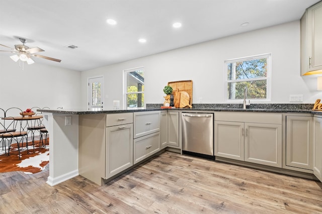 kitchen featuring light wood finished floors, visible vents, a sink, dishwasher, and a peninsula