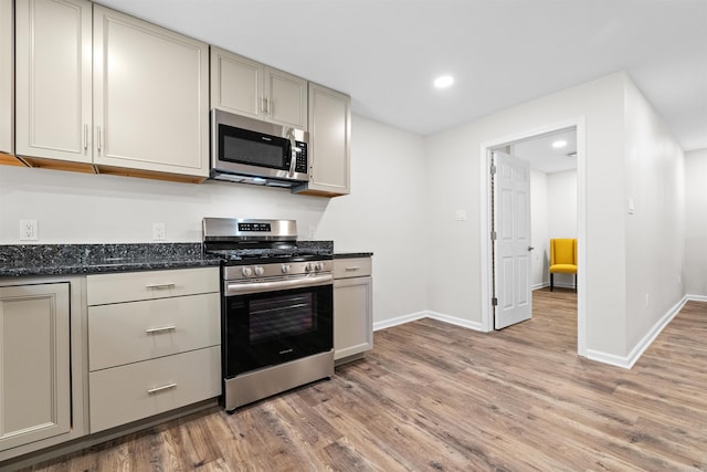 kitchen featuring light wood-style flooring, recessed lighting, stainless steel appliances, baseboards, and dark stone counters