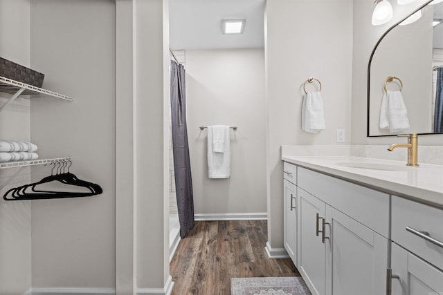 bathroom featuring curtained shower, vanity, baseboards, and wood finished floors