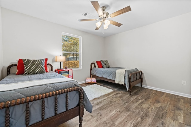 bedroom featuring a ceiling fan, baseboards, and wood finished floors