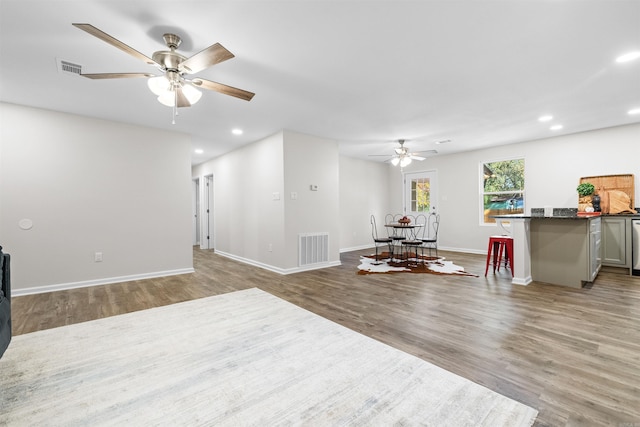 living room featuring baseboards, visible vents, wood finished floors, and recessed lighting